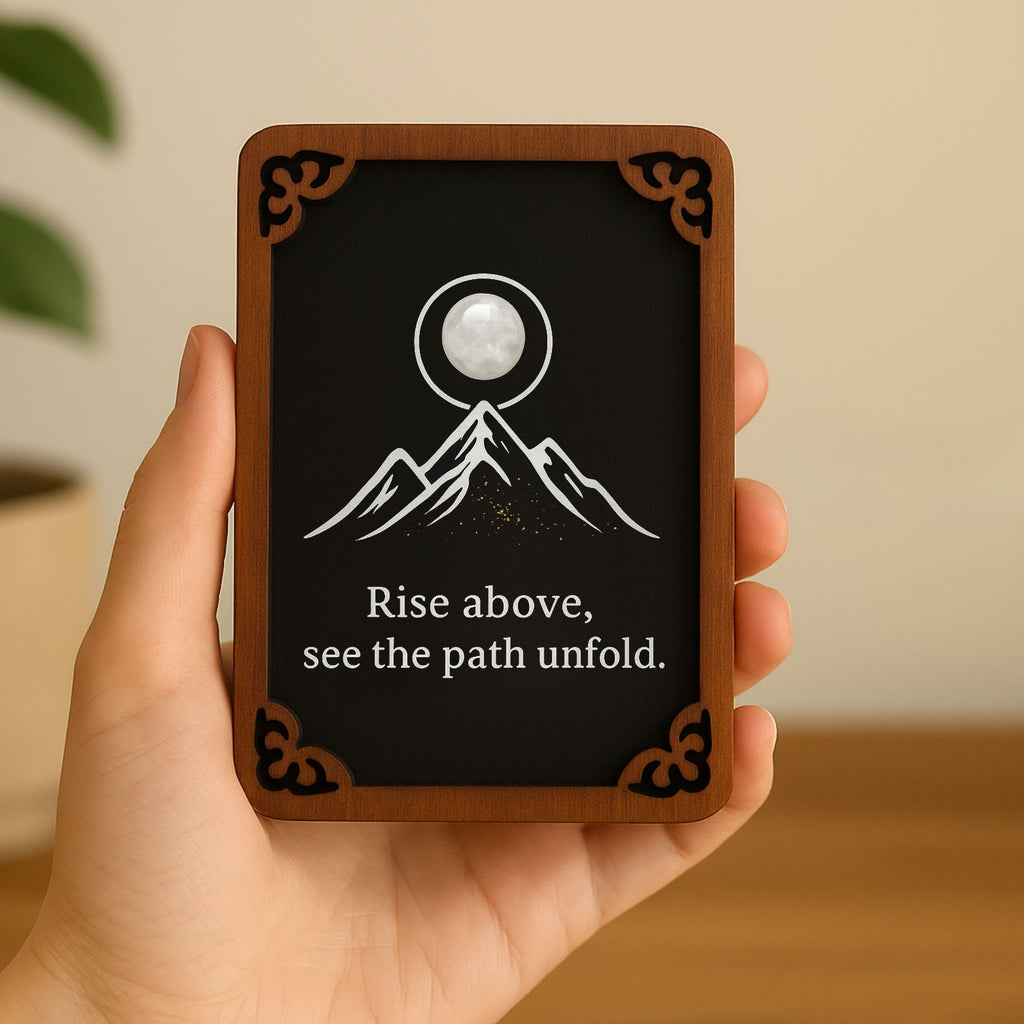 Hand-painted wooden mountain totem card with white gemstone accent, text “Rise above, see the path unfold.” Shown held in hand against a neutral background, highlighting size and craftsmanship.